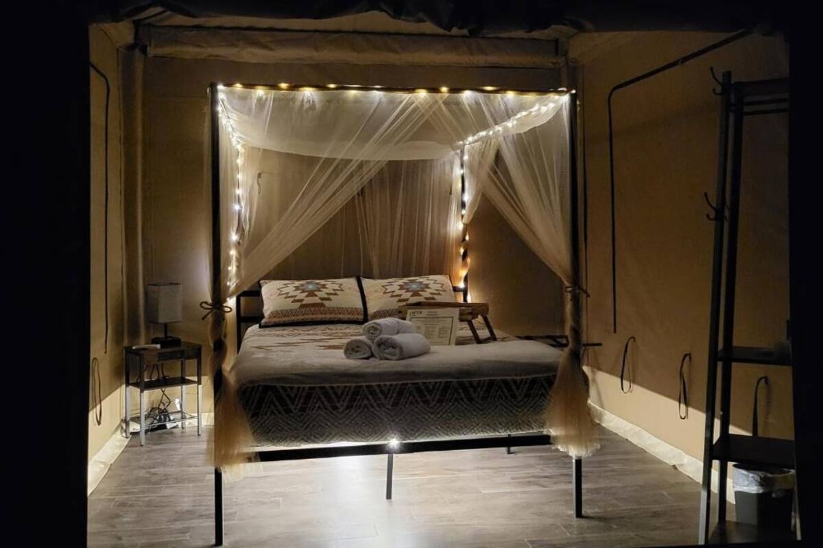 A tent-style bedroom with a canopy bed, bedside tables, and a nightstand.
