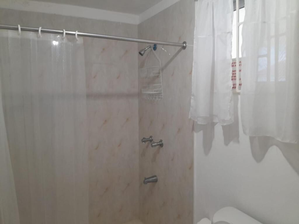 A shower area with a curtain rod, a showerhead, and a towel rack.