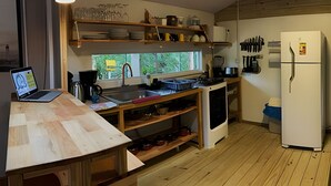 A kitchen with a wooden countertop, a laptop, a coffee maker, a sink, a stove, and a refrigerator. - Villa dos Sonhos Vá de Caiaque Até o Mar (São Francisco do Sul)