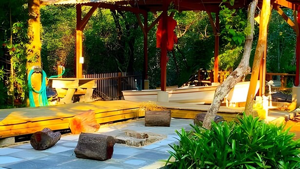 A covered outdoor area with a stone floor, wooden benches, and a pergola structure. - Villa dos Sonhos Vá de Caiaque Até o Mar (São Francisco do Sul)