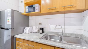 A modern kitchen with a stainless steel refrigerator, a microwave, a coffee maker, and a sink. - Espacio Lira - 1D & Wifi (Santiago)