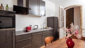 A modern kitchen with stainless steel appliances, a wooden dining table, and a vase with flowers. - Artist's room 1.5 - the minimalist (Gera)
