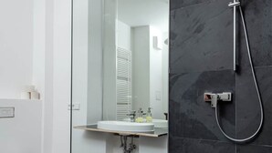 A modern bathroom with a glass shower enclosure, a white sink, and a toilet. - Artist's room 1.5 - the minimalist (Gera)