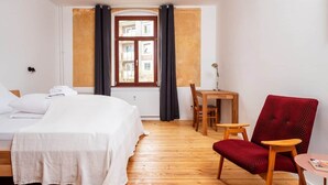 Une chambre d’hôtel avec un lit, un bureau, une chaise et une fenêtre avec des rideaux.