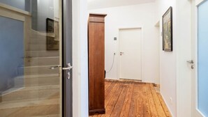 Un couloir avec un plancher en bois, une porte et un meuble en bois.