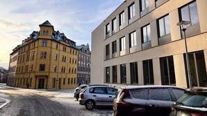 Une rue bordée de voitures garées et un immeuble doté d’une façade moderne.