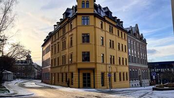 Ein Eckgebäude mit gelber Fassade, zahlreichen Fenstern und markantem architektonischen Stil.