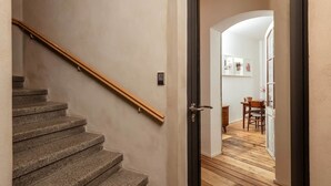Un escalier mène à une pièce dont le sol est recouvert de planches de bois, et on aperçoit à l’arrière-plan un coin repas.