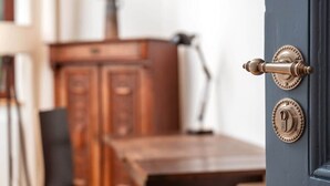 Une table de salle à manger en bois, des chaises, un buffet et une porte bleue avec une poignée en laiton.