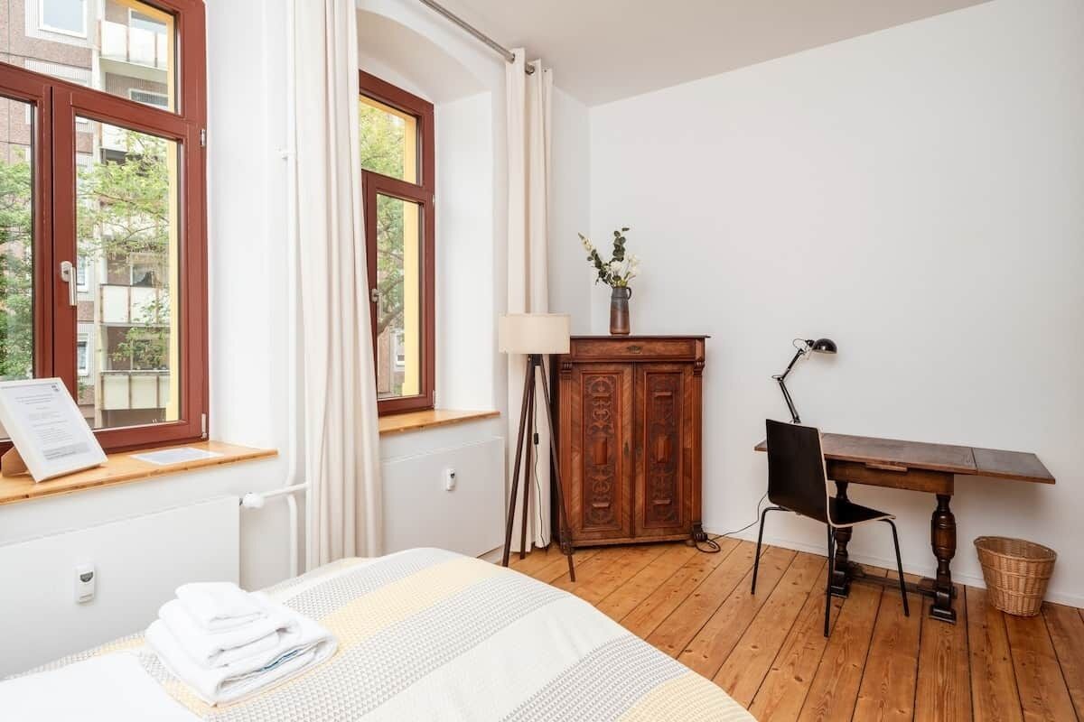 Een hotelkamer met een bed, een bureau, een stoel, een lamp en een kast.