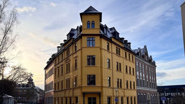 A corner building with a yellow facade, multiple windows, and a distinct architectural style. - Artist room 2.2 - the spacious one (Gera)