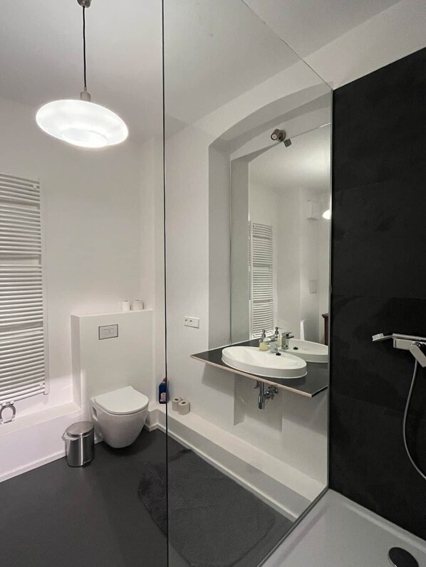 Une salle de bain moderne équipée de toilettes, d’un lavabo et d’une douche.