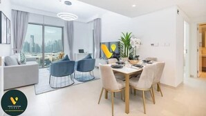 Un salon moderne avec un coin repas, de grandes fenêtres et une vue sur la ville.