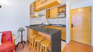 Una cocina compacta con armarios de madera, encimera negra y un reloj integrado.