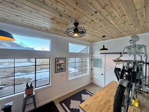 Ein Zimmer mit Holzboden, großen Fenstern, einem Motorrad und einer Skelettdarstellung.