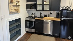 Eine moderne Küche mit schwarzen Schränken, Edelstahlgeräten und einer Holzausziehtafel.