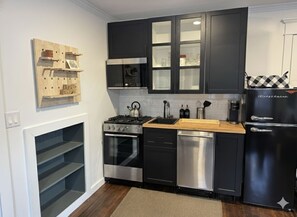 Eine moderne Küche mit schwarzen Schränken, Edelstahlgeräten und einer Holzausziehtafel.