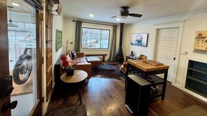Ein Zimmer mit Holzboden, einer Couch, einem Tisch, einem Kamin und einem Fernseher an der Wand.