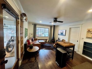 Ein Zimmer mit Holzboden, einer Couch, einem Tisch, einem Kamin und einem Fernseher an der Wand.