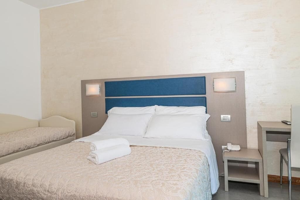 A hotel room with a large bed, two bedside tables, and a desk with a chair.