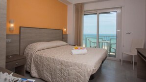 Een hotelkamer met een bed, nachtkastje, bureau en uitzicht op het balkon.