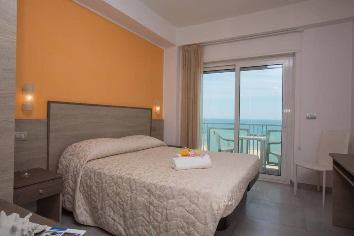 Une chambre d’hôtel avec un lit, une table de chevet, un bureau et une vue sur le balcon.