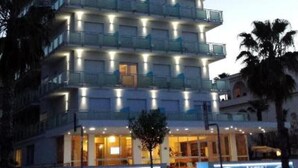 Een hotel met meerdere verdiepingen, balkons, een zwembadgedeelte en een bord waarop staat Altis Hotel.