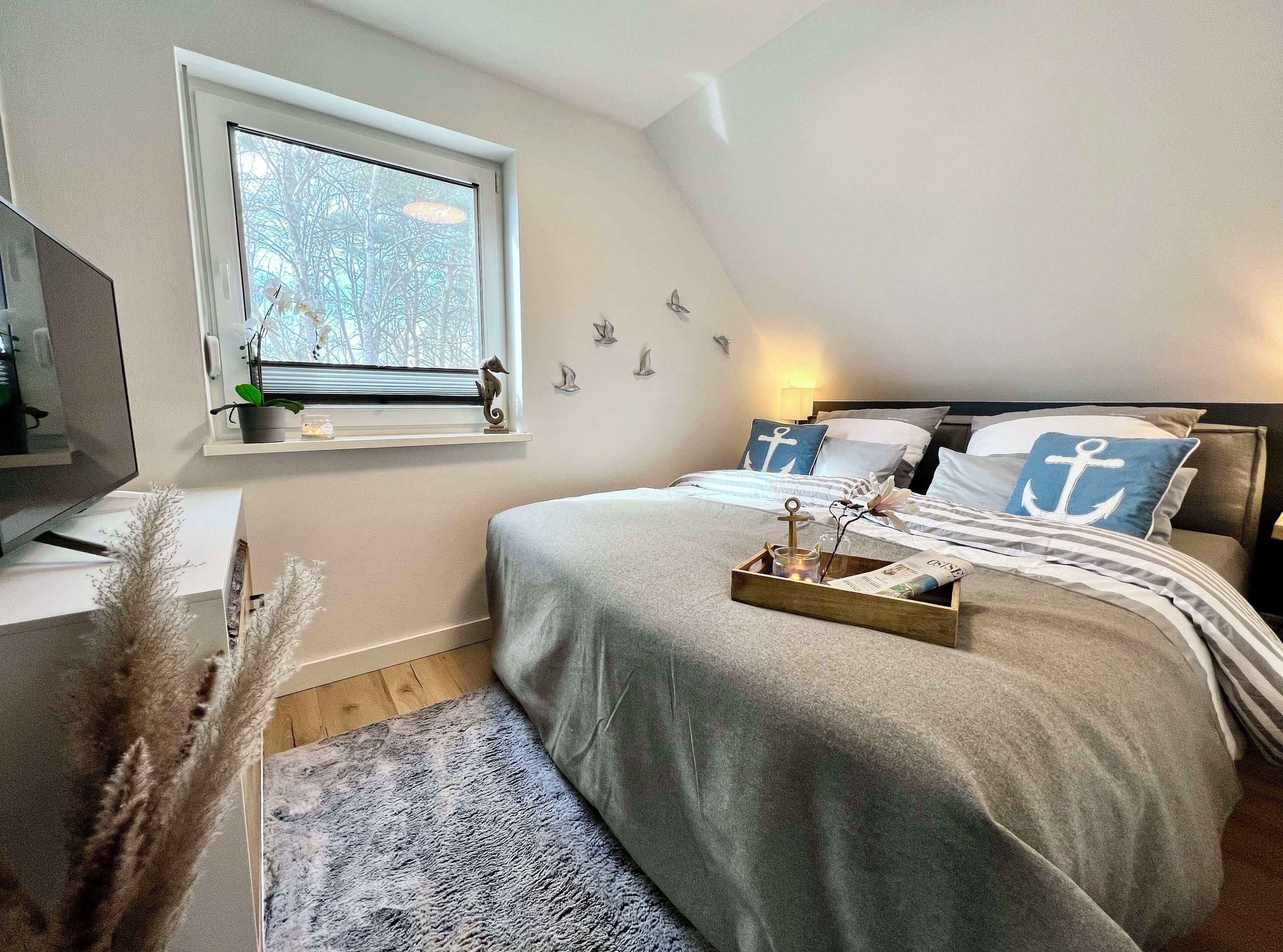 Ett sovrum med en säng, ett fönster, ett sängbord och en lampa.