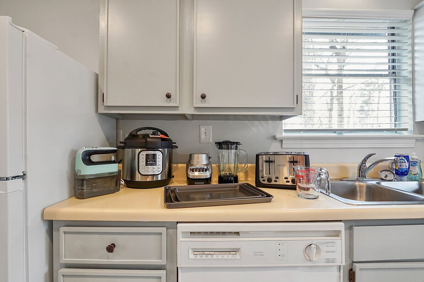 A compact kitchenette with a built-in oven, a blender, a toaster, and a sink.