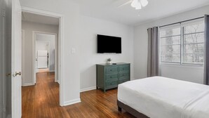 Ein Schlafzimmer mit einem Bett, einem Schminktisch, einem Fernseher und einem Deckenventilator.