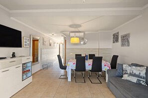 Eine moderne Küche mit Essbereich, einem Flachbildfernseher und einer Couch mit reisebezogenen Kissen.