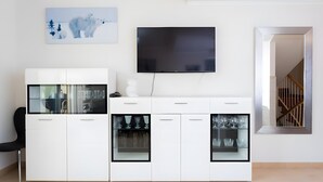 Ein modernes Wohnzimmer mit einem weißen Schrank, einem Flachbildfernseher und einem gerahmten Bild eines Eisbären.