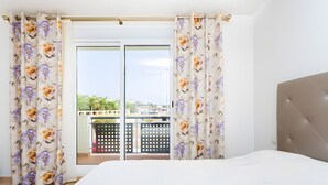 Ein Schlafzimmer mit Bett, Vorhängen und Blick auf einen Balkon.