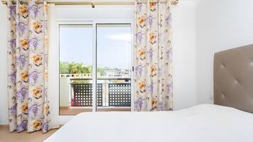 Et soveværelse med seng, gardiner og udsigt til en balkon.