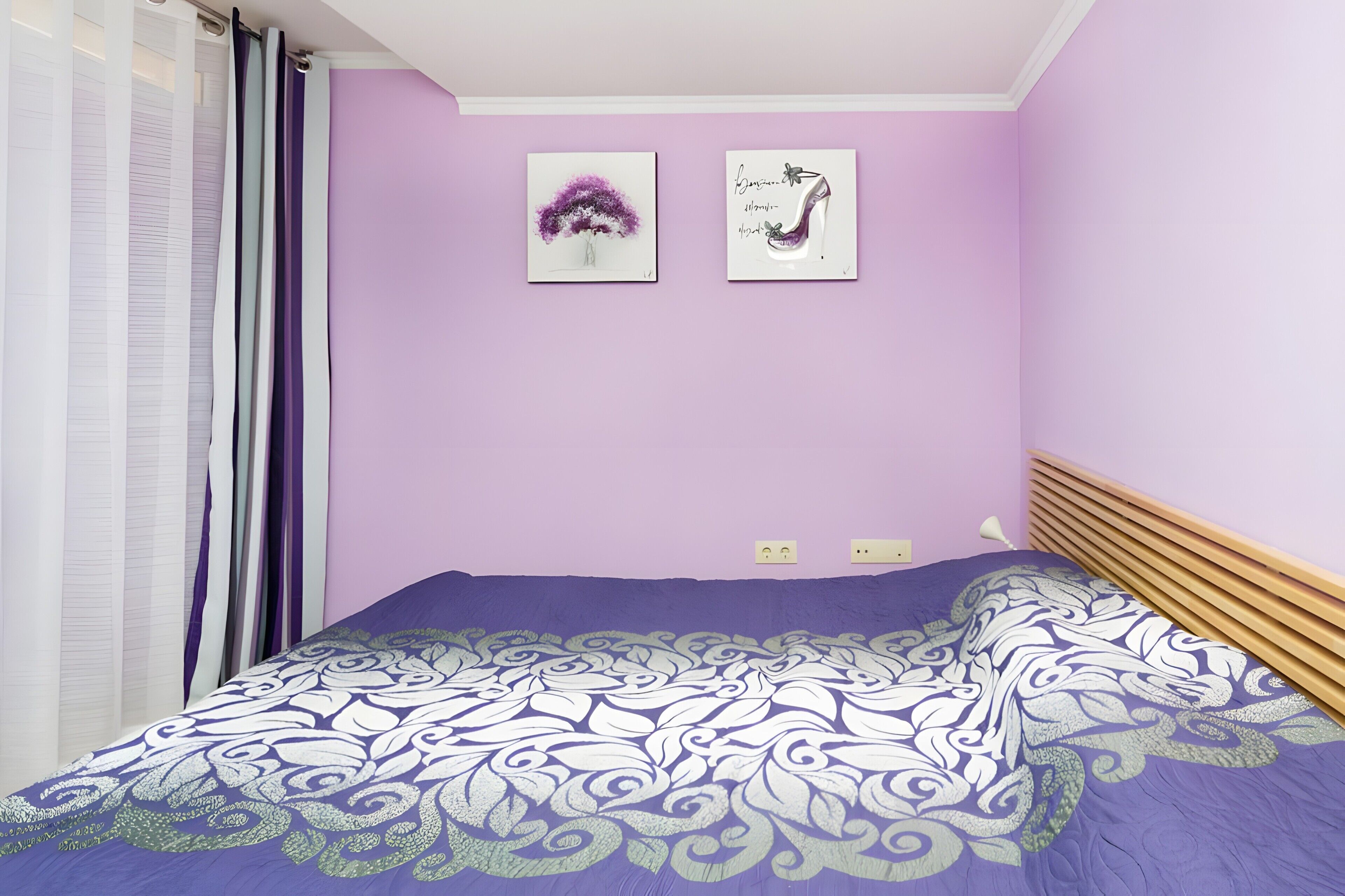 Un dormitorio con cama, una ventana con cortinas y dos obras de arte colgadas en la pared.