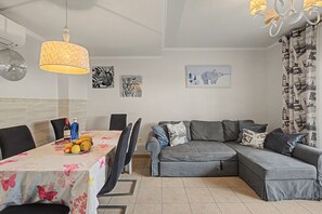 A modern living space with a dining area, a sofa set, and artwork on the walls. - Vacation Apartment 'Oasis Fañabe Townhouse' with Mountain View, Wi-Fi and Air Conditioning (Costa Adeje)