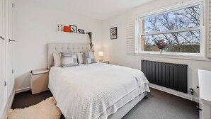 Een slaapkamer met een groot bed, een nachtkastje, een raam met uitzicht en een radiator.