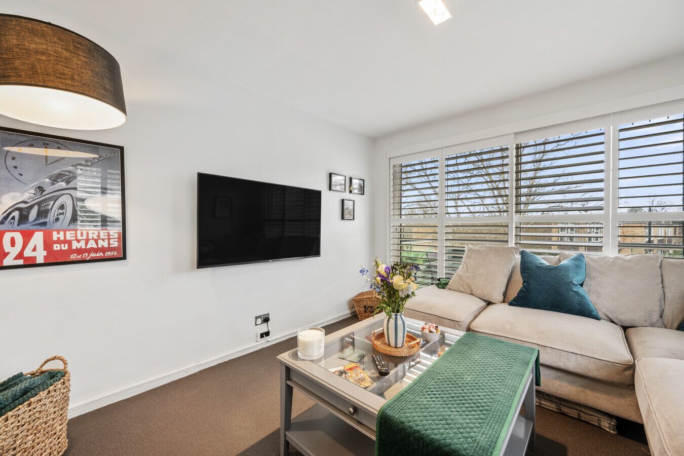 A modern living room with a sofa, a coffee table, a TV, and a window with blinds.