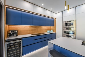Eine moderne Küche mit blauen Schr änken, einer Holzvertäfelung und eingebauten Geräten, darunter eine Kaffeemaschine und ein Backofen.