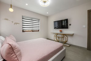 Ein modernes Schlafzimmer mit Bett, Schreibtisch und Fernseher.