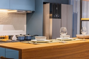 Une cuisine moderne avec un îlot central en bois, des appareils en acier inoxydable et des armoires bleues.