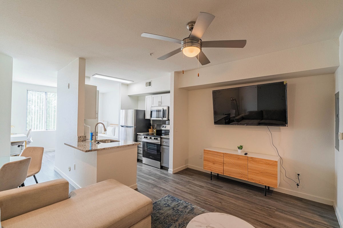 A modern living room with a sofa, a coffee table, and a TV mounted on the wall.