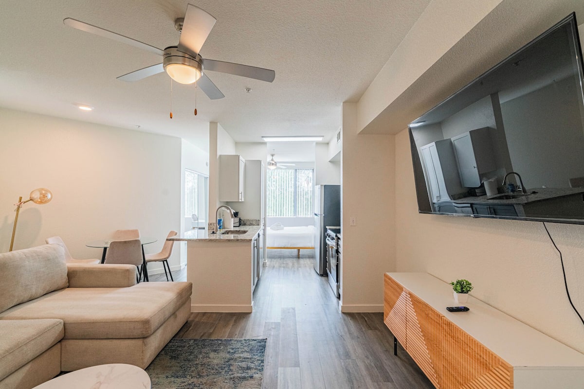 A modern living room with a sofa, a coffee table, and a TV mounted on the wall.