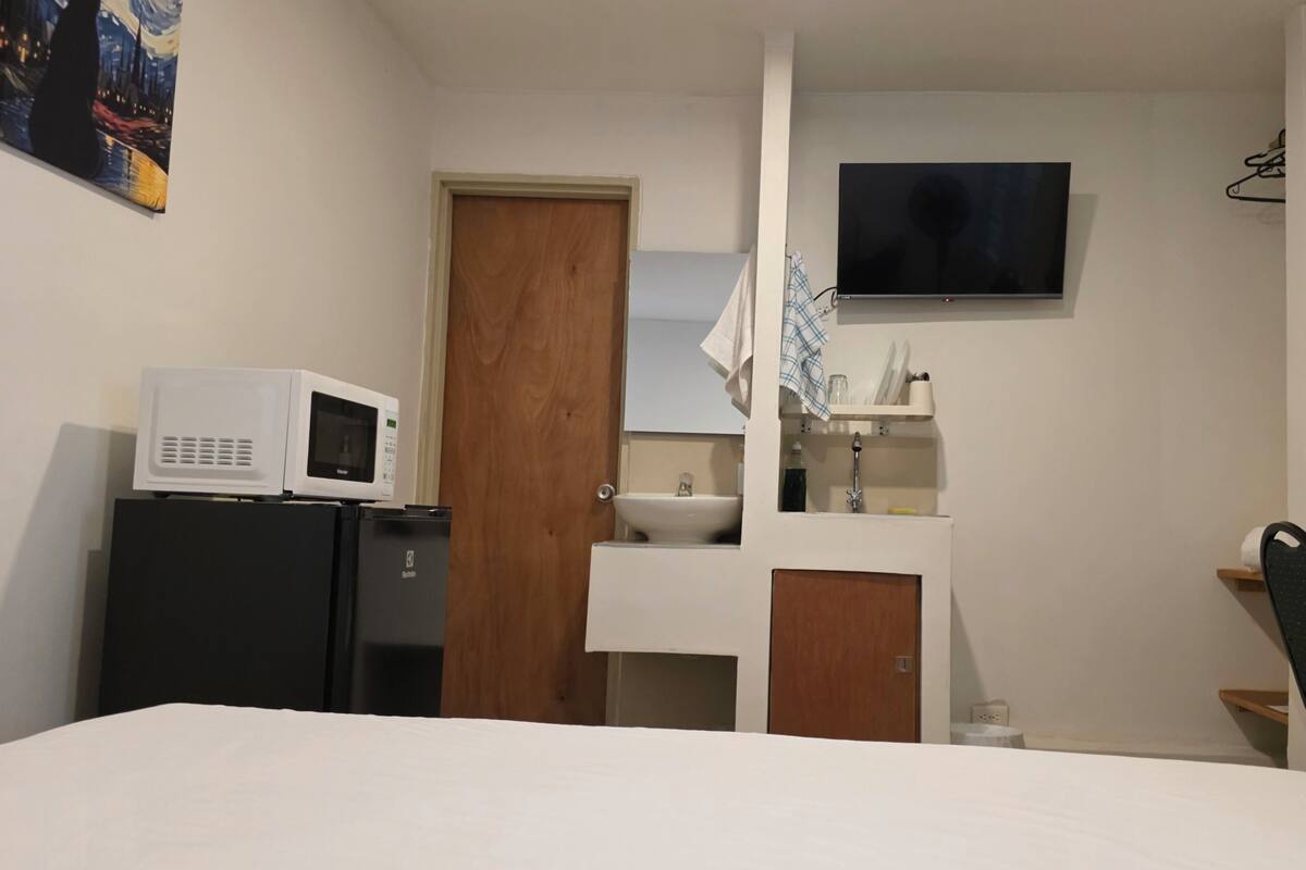 Une chambre d’hôtel équipée d’un lit, d’un four à micro-ondes, d’un lavabo, d’une télévision et d’une chaise.