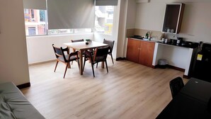 A modern apartment with a dining area, kitchen, and a balcony with a view of buildings. - ABC-53 (Medellín)
