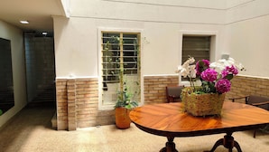 A spacious indoor area with a wooden table, potted plants, and a brick wall. - ABC-53 (Medellín)