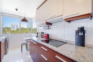 A modern kitchen with a large window, a built-in stove, and a coffee maker.