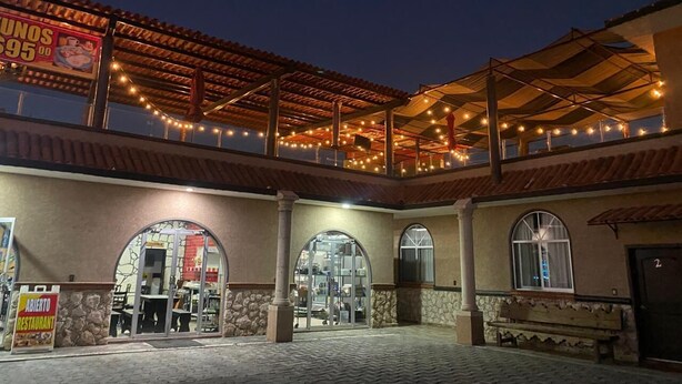A restaurant with outdoor seating, covered by a pergola, and a sign advertising a special offer. - Enrique Resendiz Vega (Colon)