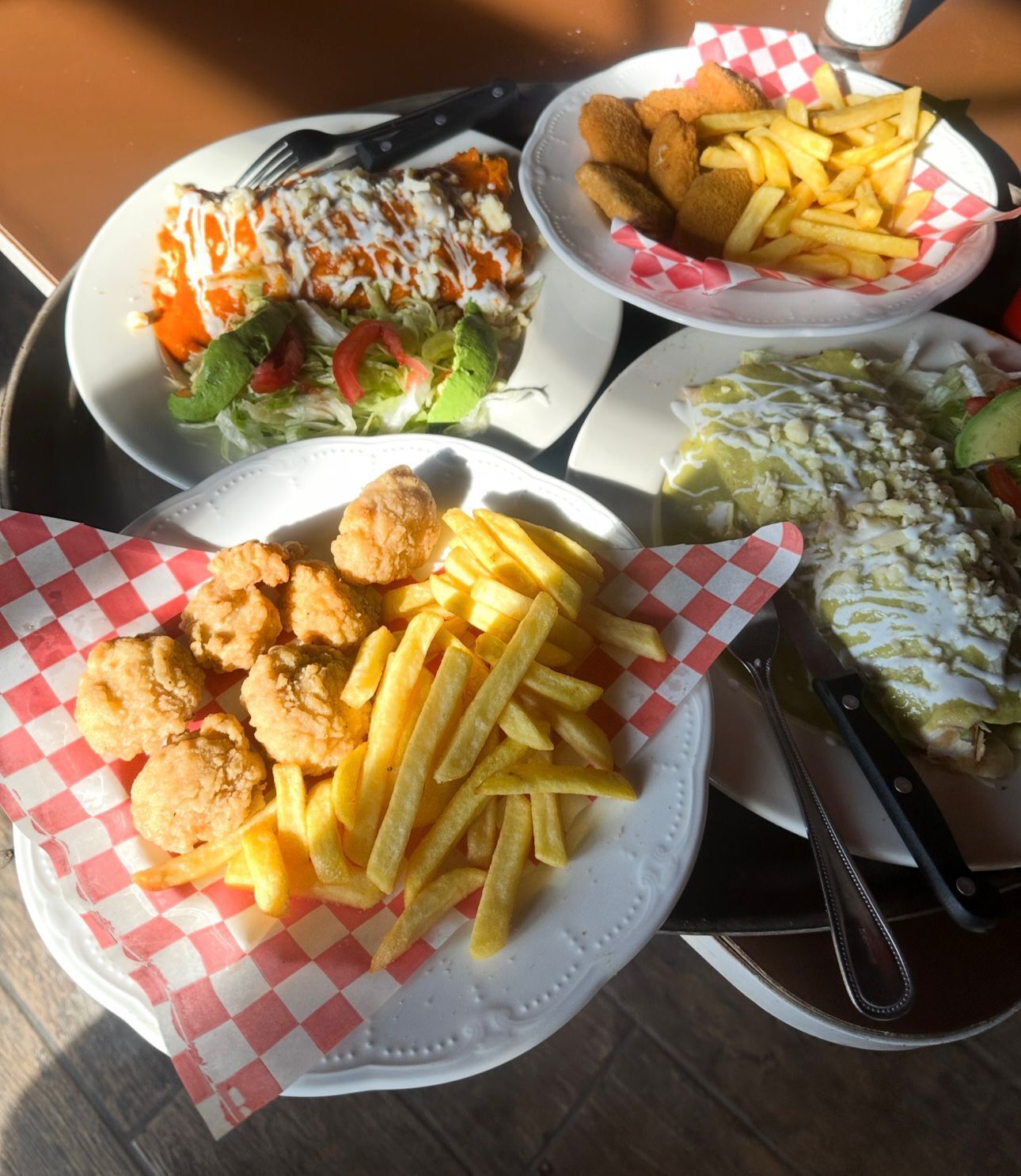 Ein Tisch mit verschiedenen Speisen, darunter ein Salat, Pommes und ein Gericht mit weißer Soße.