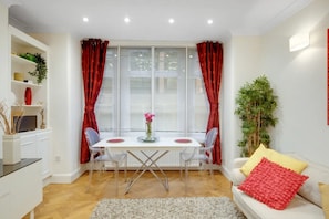 A modern dining area with a white table, two chairs, and a vase of flowers. - Prime Location 2 bed Flat | Bond St, Selfridges - Pass the Keys (London)